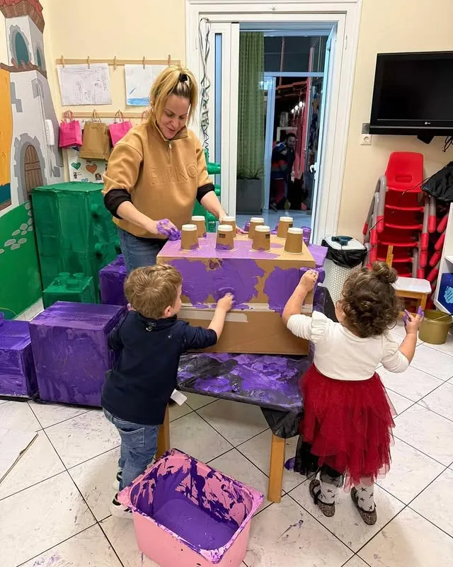 Παιδιά και παιδαγωγός βάφουν μεγάλη κατασκευή